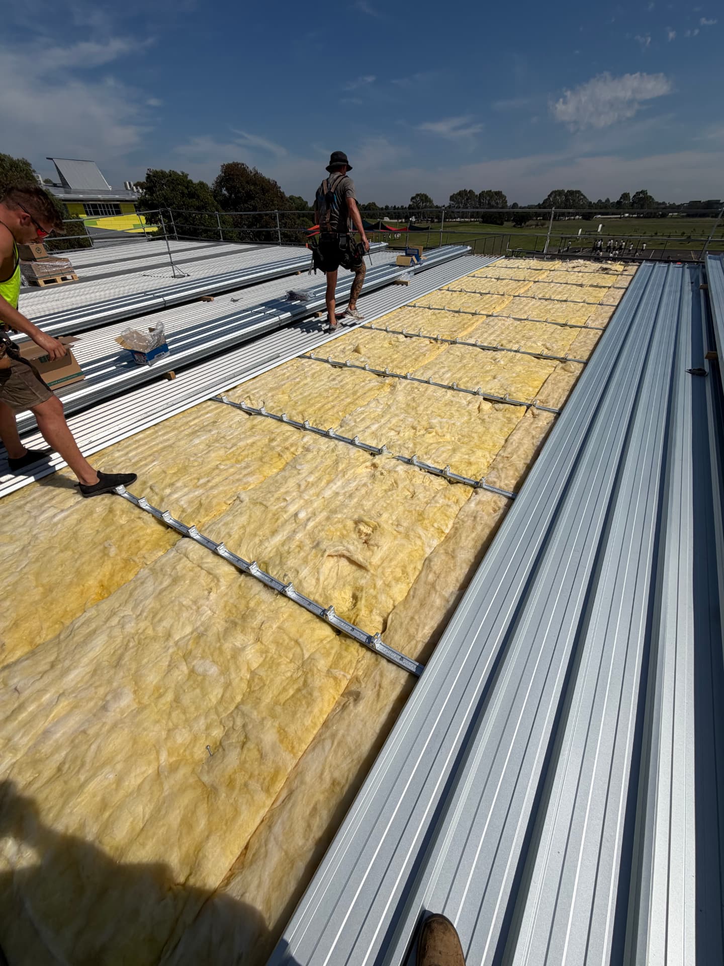 Roofers installing new insulation, battens and corrugated Colorbond roofing sheets